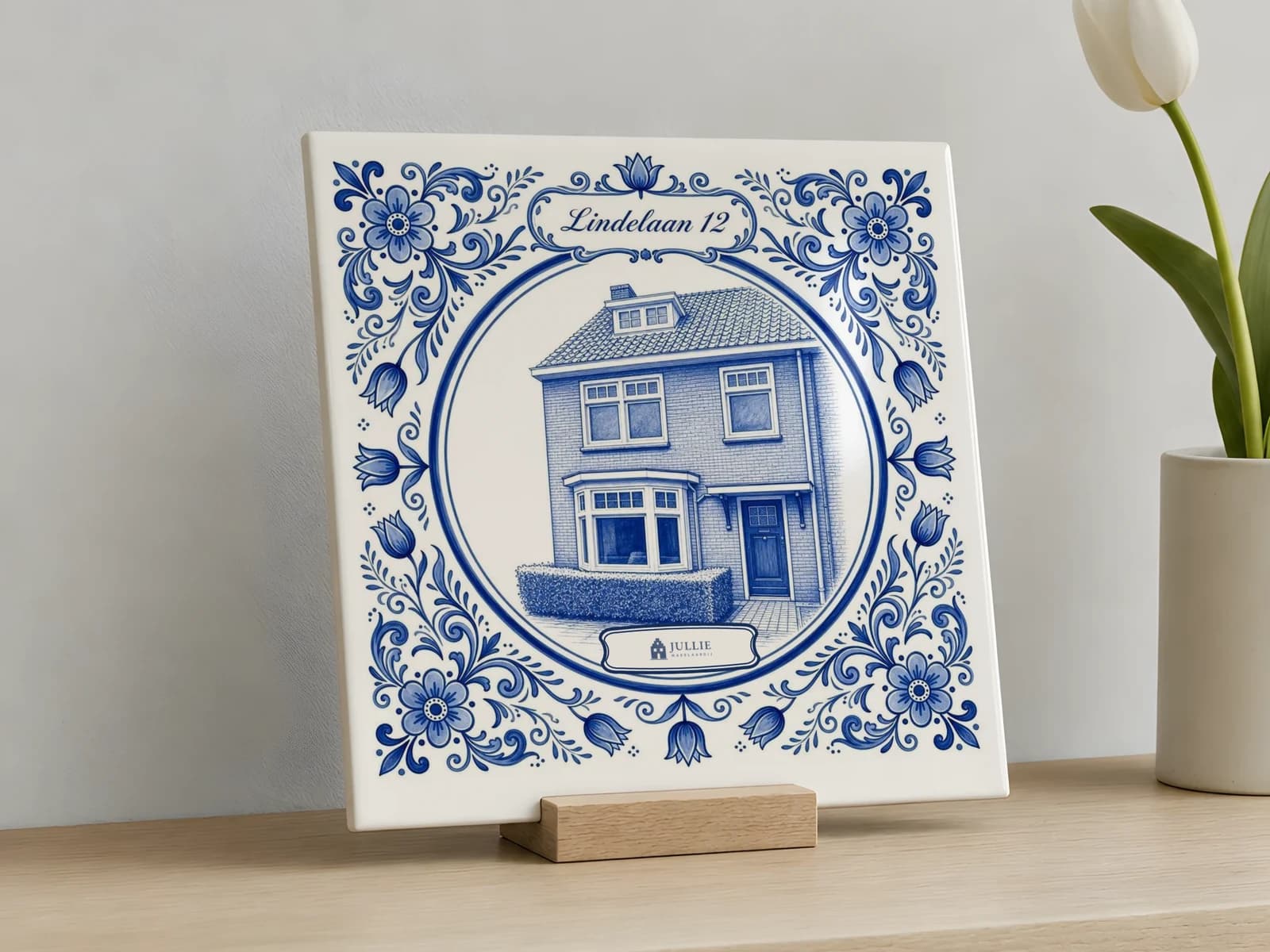 Delfts blauw tegeltje van een woning op een houten houder